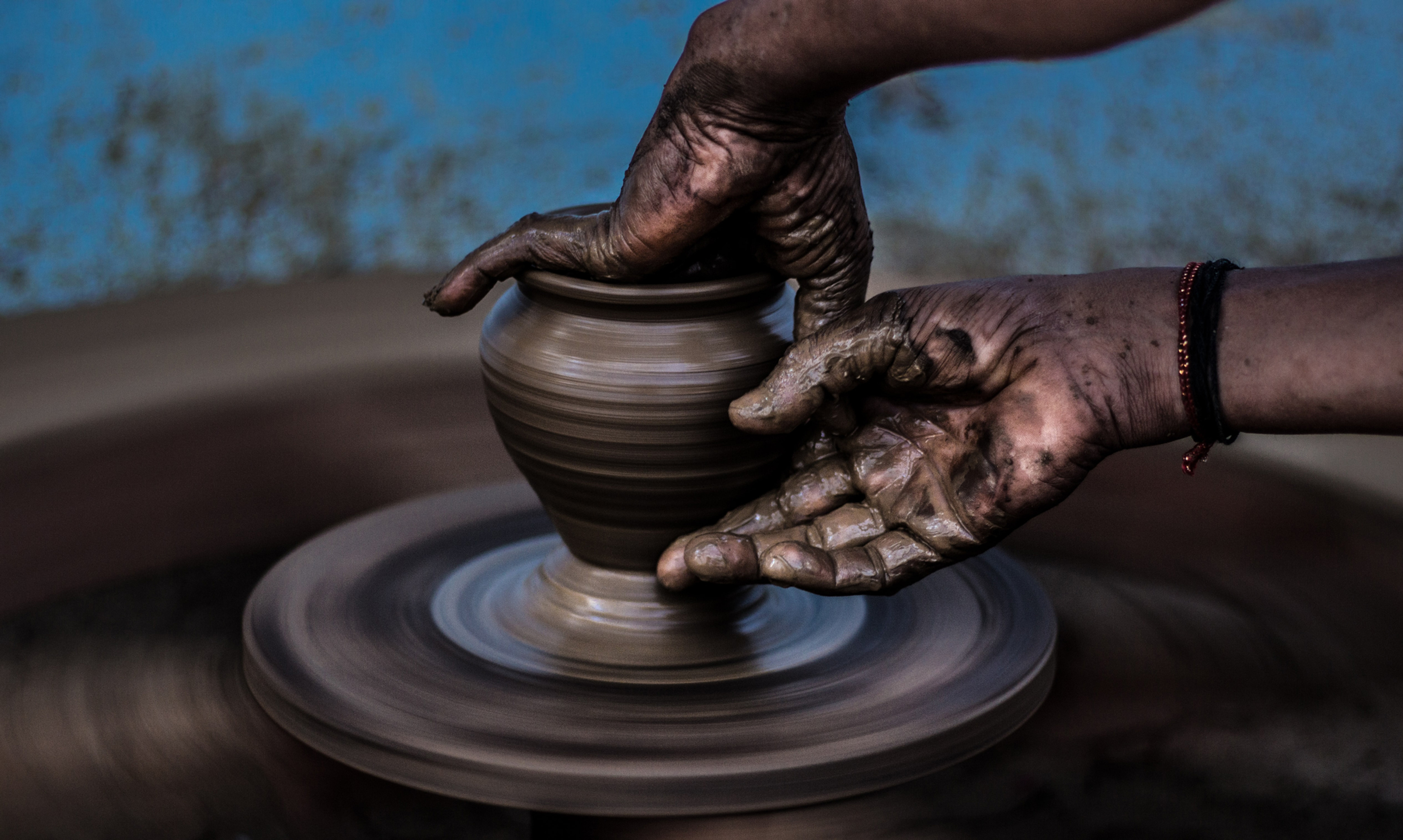 Hands shaping clay on a spinning pottery wheel